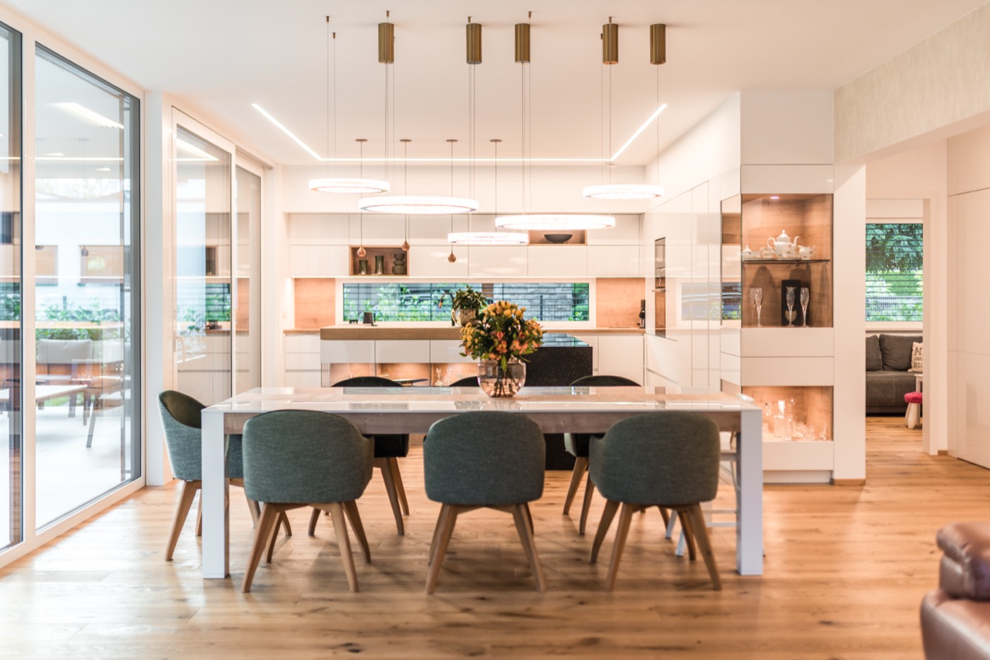 Hell gestalteter Ess- und Küchenbereich eines modernen Wohnhauses von Lumar Haus mit hochwertiger Beleuchtung und Parkettboden.