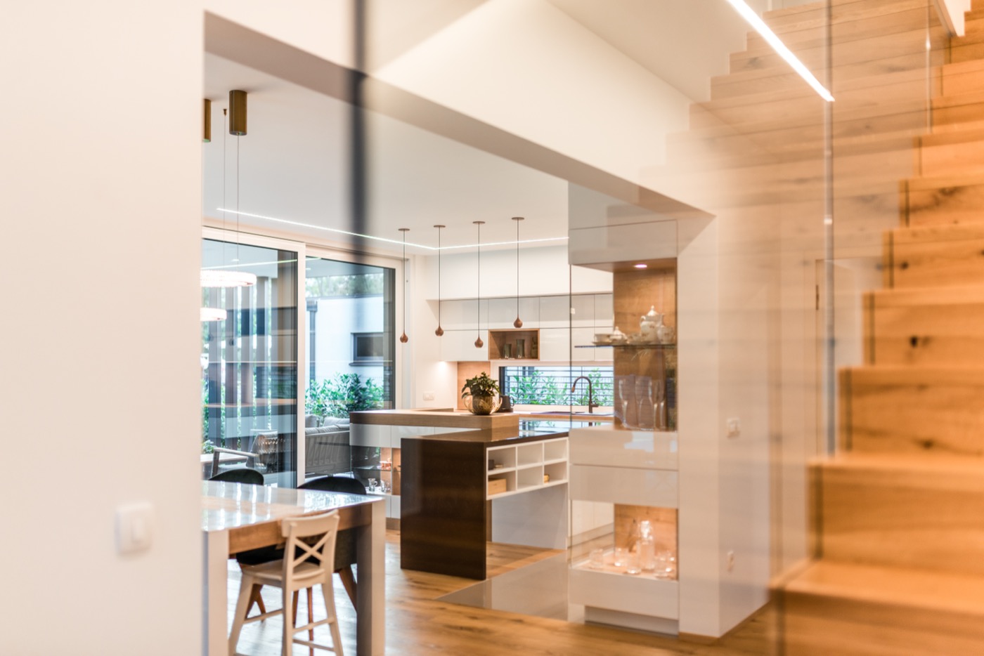 Offener Wohnbereich eines Hauses von Lumara Haus mit moderner Holztreppe mit Glasgeländer.