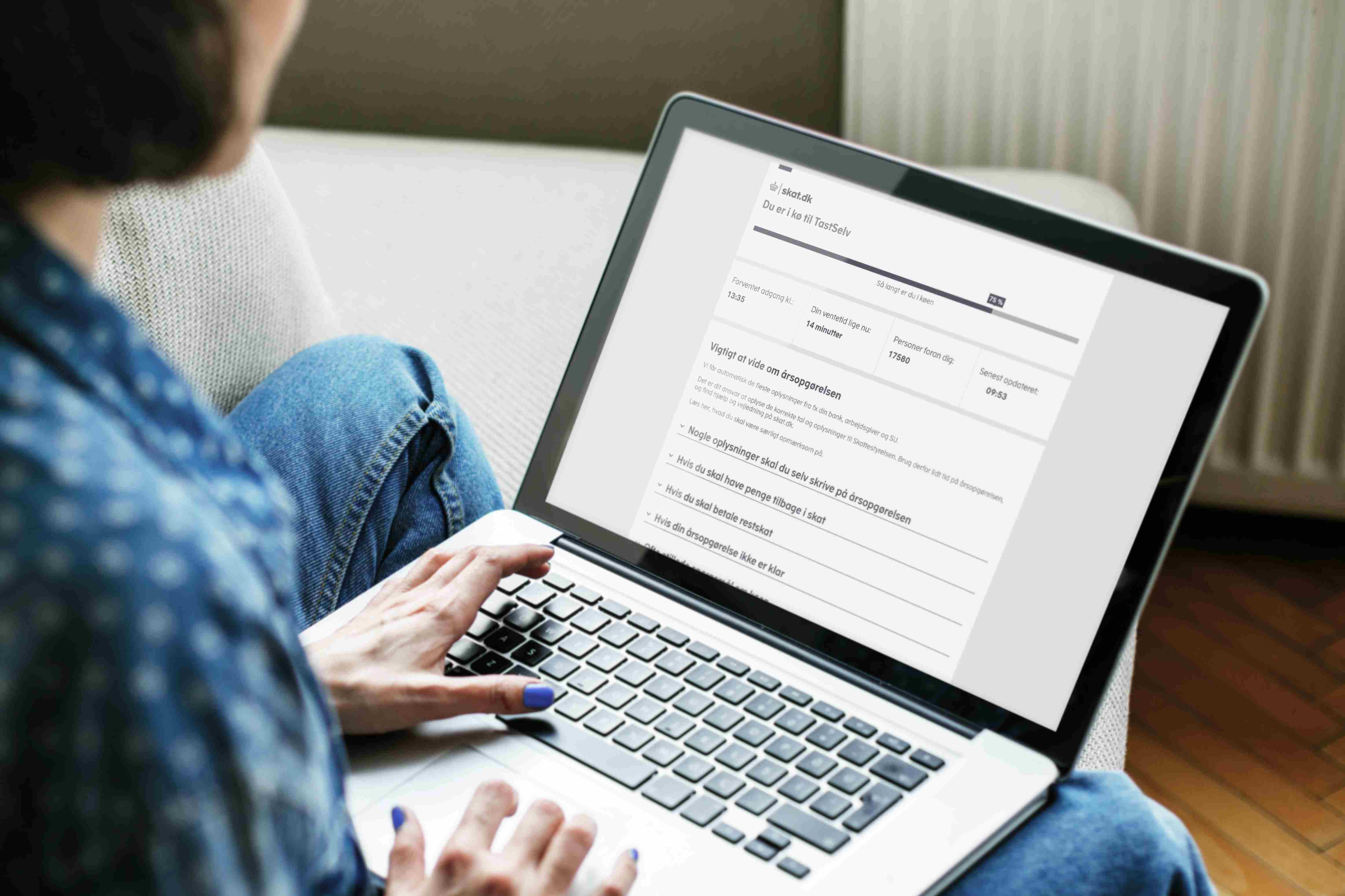 A person is sitting with a laptop on their lap and logging into skat.dk via TastSelv to view their tax account.