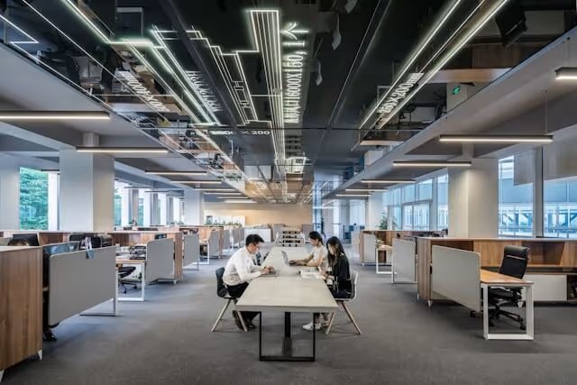 Modern open-plan office with people working at a shared table.