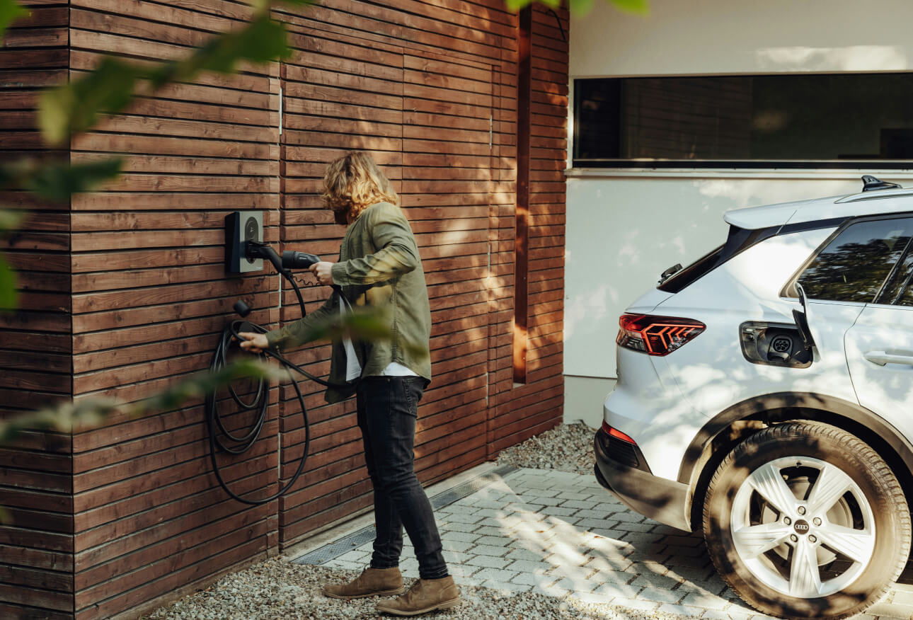 Privatperson laddar elbilen i en laddbox på garageväggen hemma vid villan