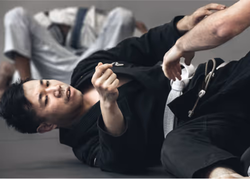 A Jiu-Jitsu student in a black gi focusing during training