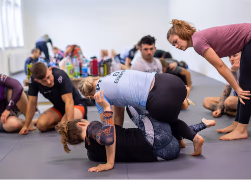 A mixed group of Jiu-Jitsu practitioners training on the mats, focusing on drills