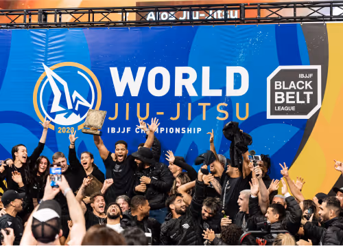 A group of Jiu-Jitsu practitioners celebrating a championship victory in front of the World Jiu-Jitsu banner