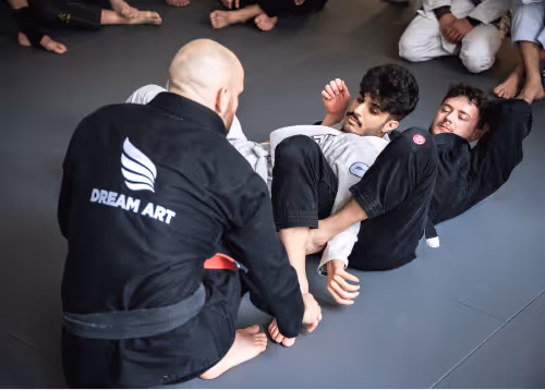 A Jiu-Jitsu instructor demonstrating a technique to students on the mat