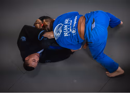 Two Jiu-Jitsu athletes sparring on the mat, practicing techniques