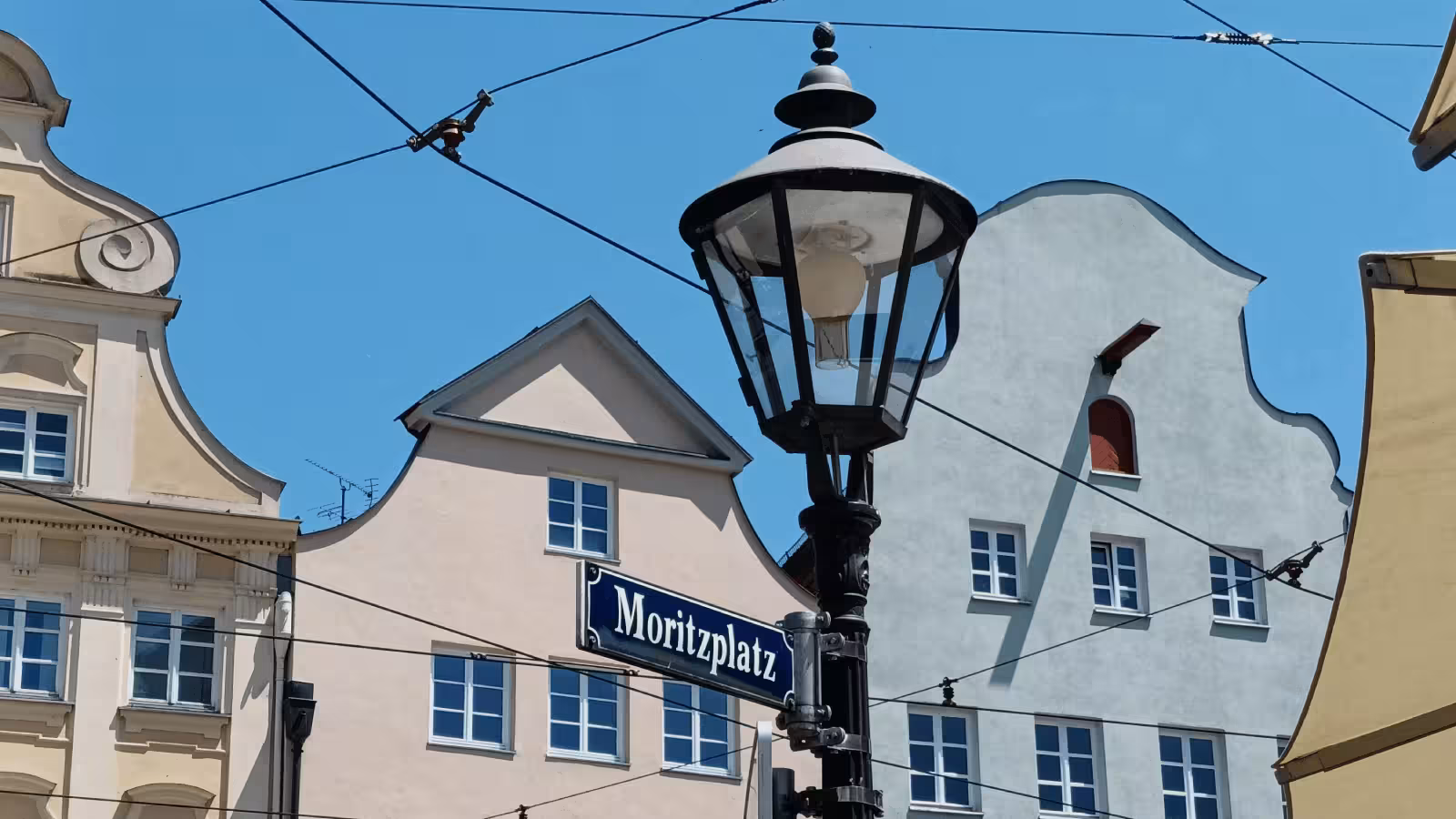 Foto vom Strassenschild Moritzplatz mit Häusern im Hintergrund nur wenige von unserem SEO Freelancer Augsburg Büro entfernt