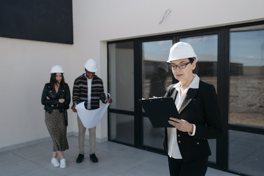 seller in suit and clients standing by house windows