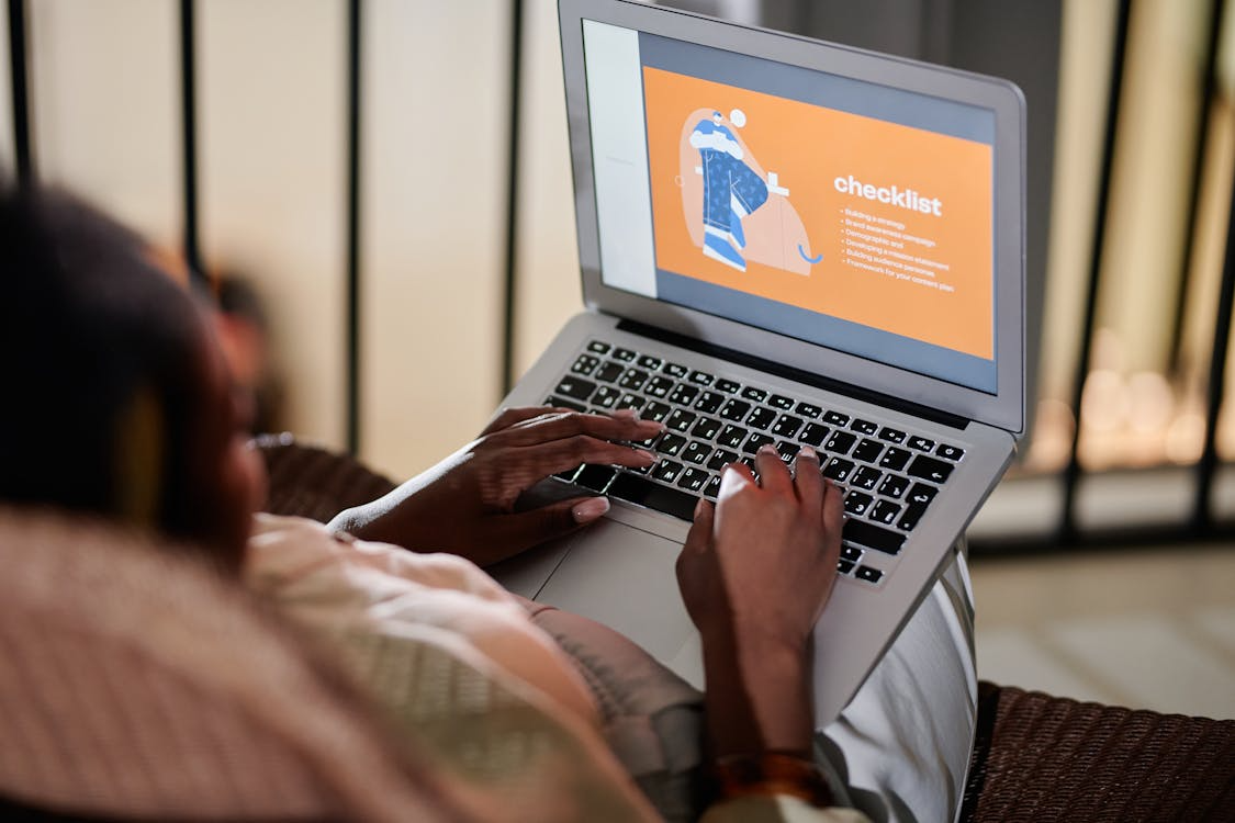 Person Sitting on Sofa Using Laptop