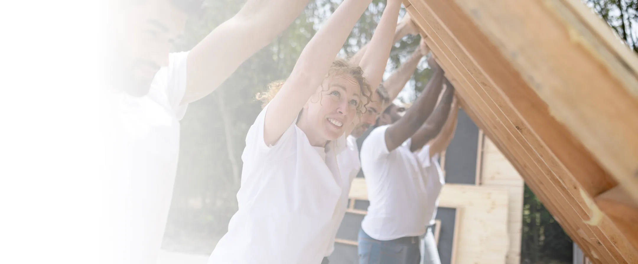Volunteers hoisting up a wall for a house built out of wood