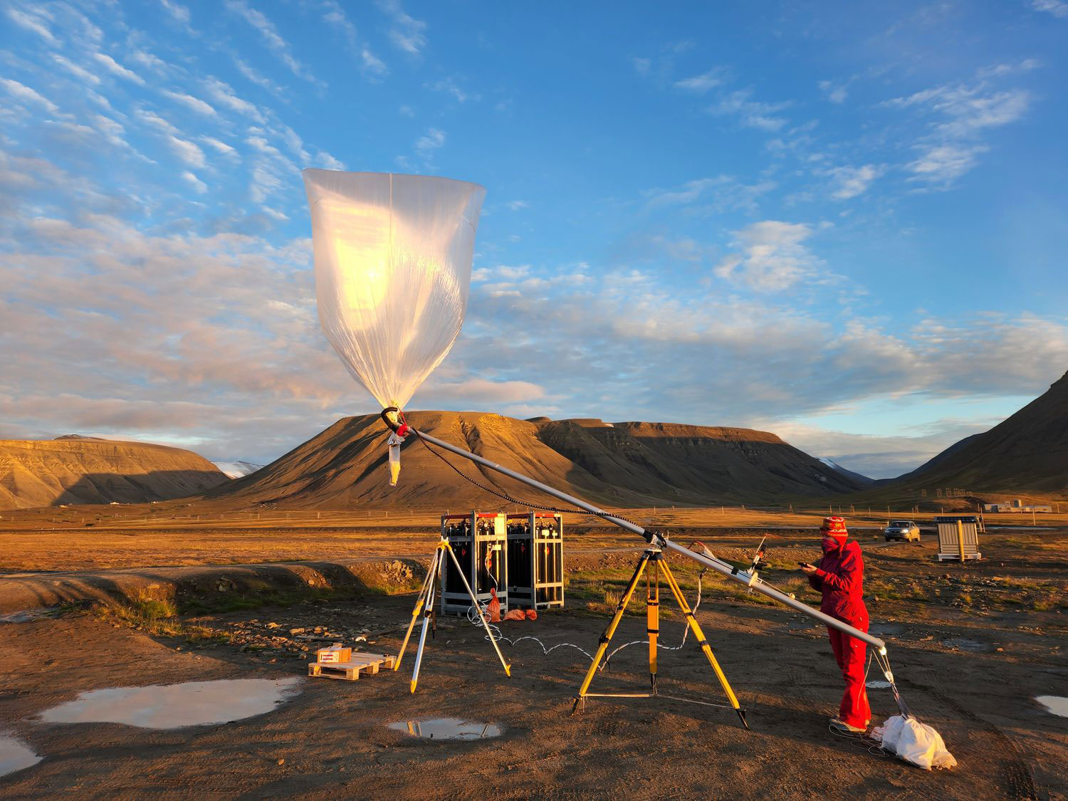 Female engineer operating balloon launch rig in a scenic mountainous background
