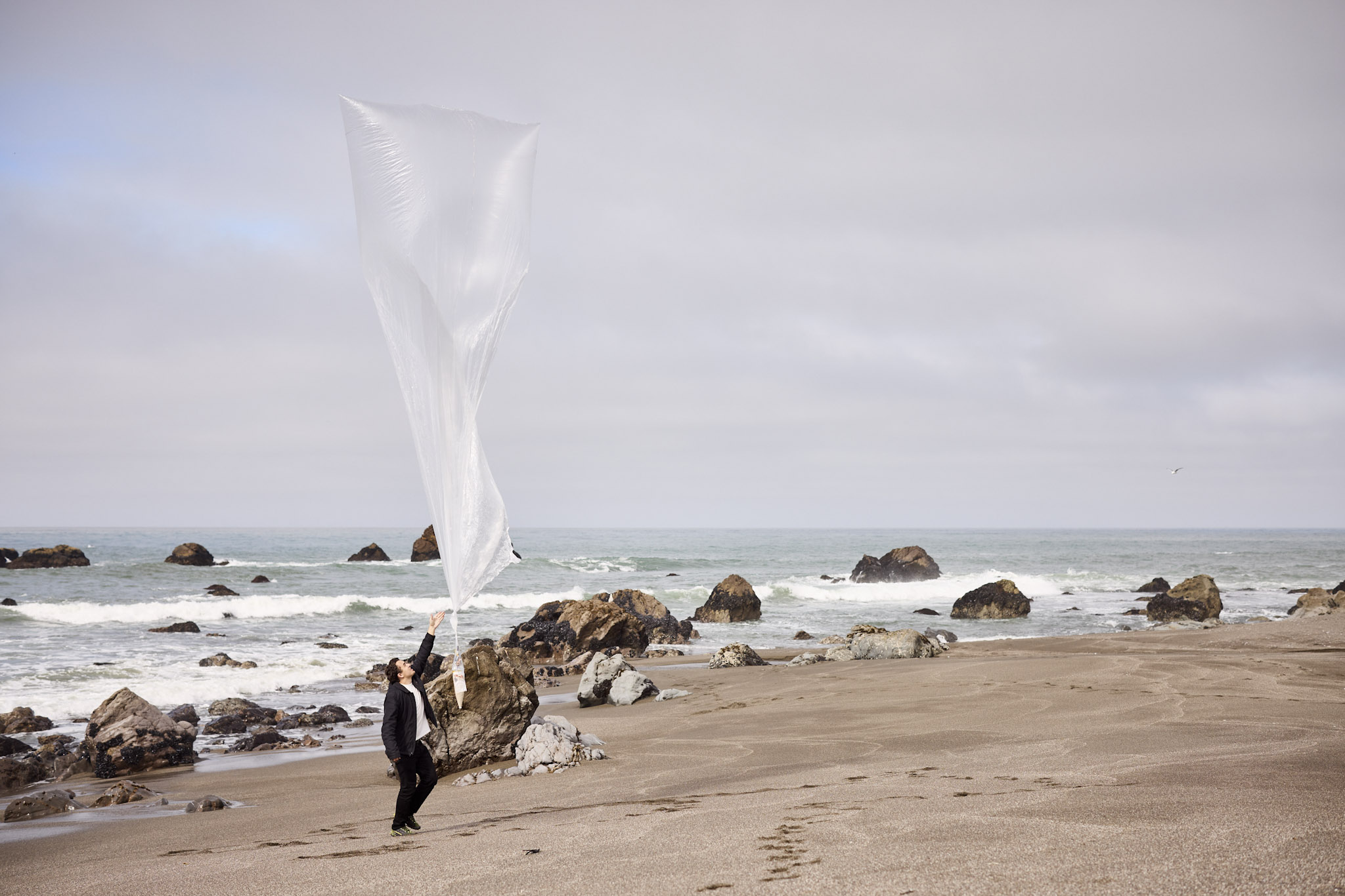 Man releasing balloon on beach by hand