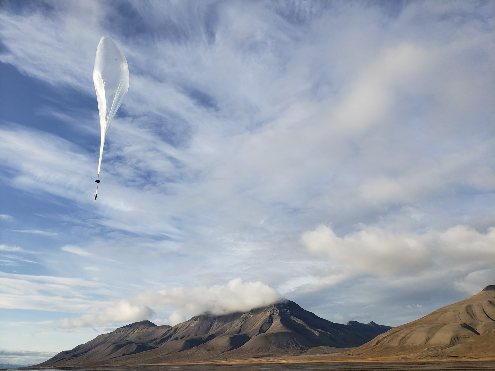 Balloon flying in cloudy sky over the mountains