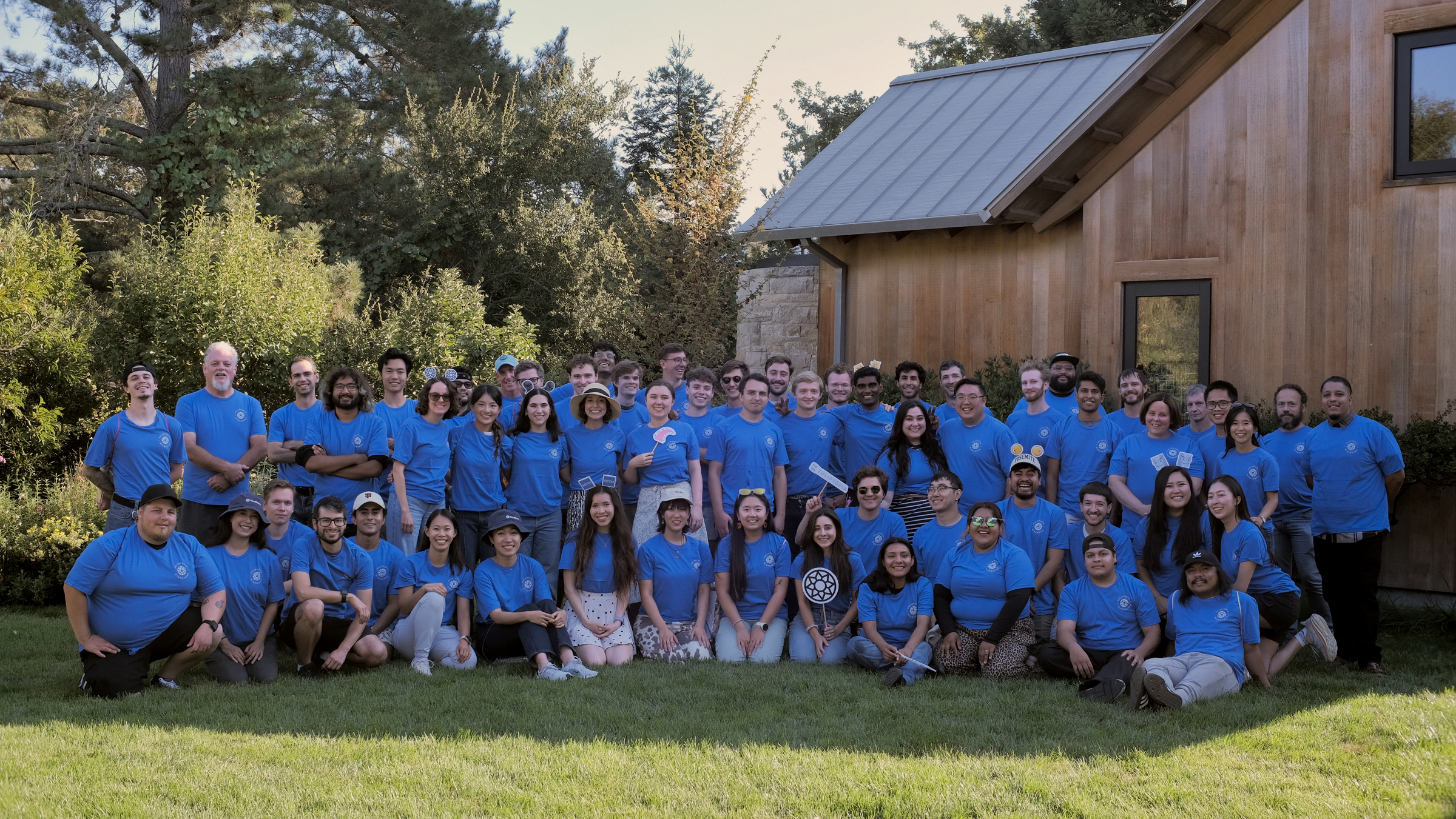 Team photo consisting of approx 50 people wearing blue WindBorne shirts on a grassy lawn.
