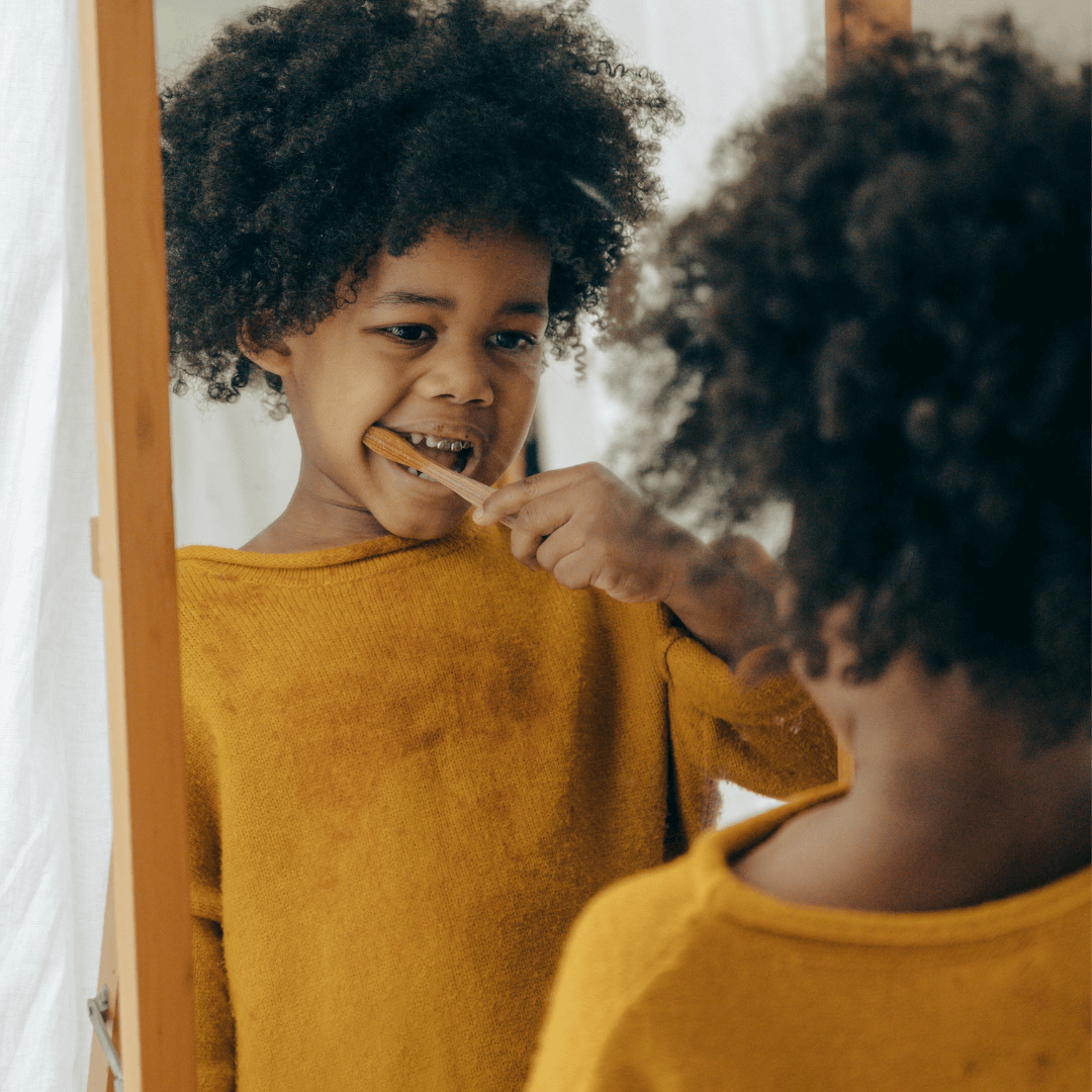 a child brushing her teeth in a mirror