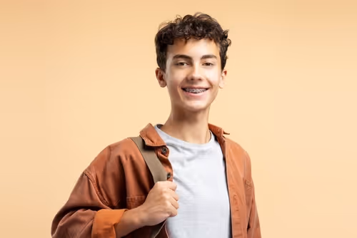 chico sonriendo con frenos, frenillo, brackets dentalles