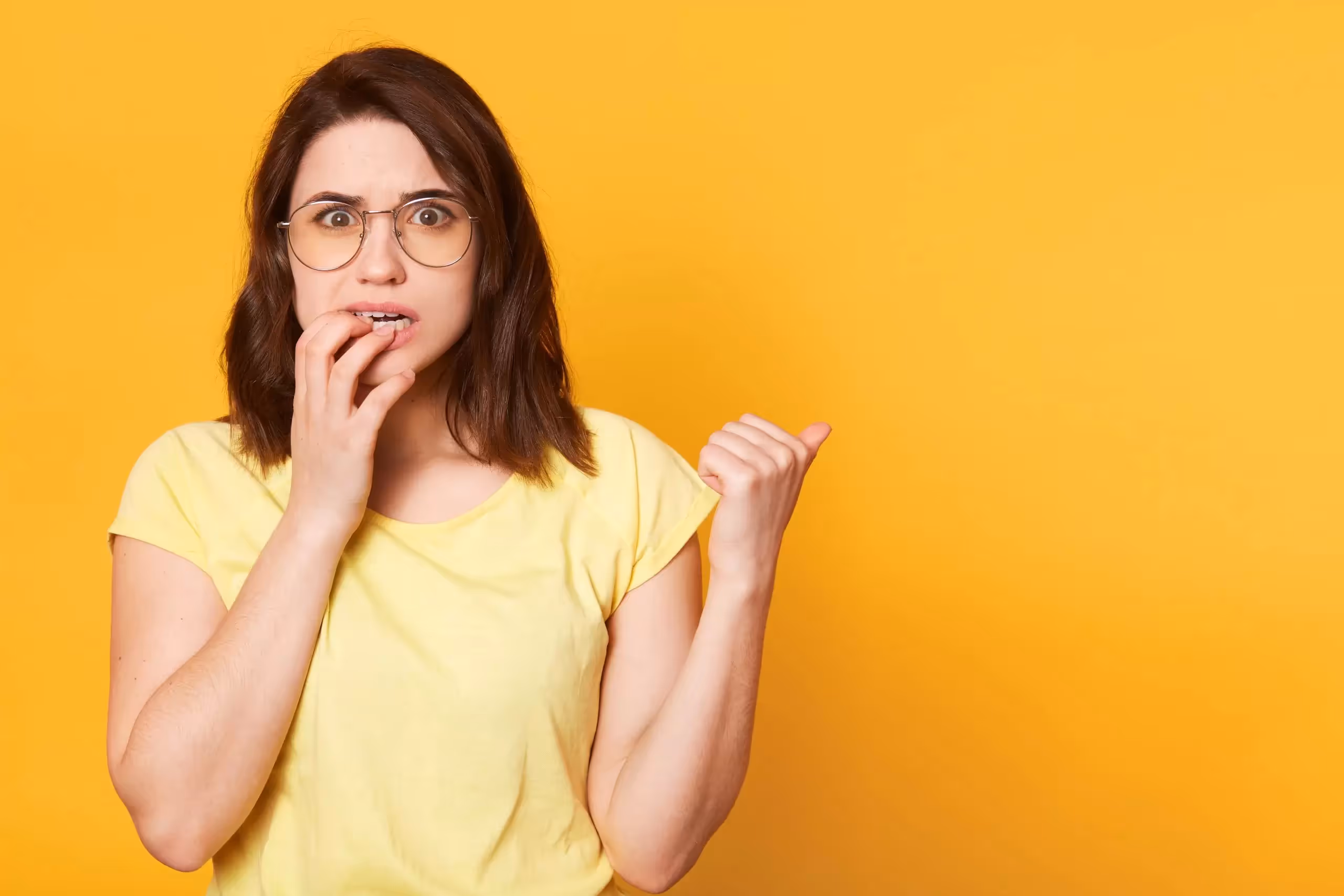 Mujer mordiéndose los dedos preocupada por sus dientes amarillos