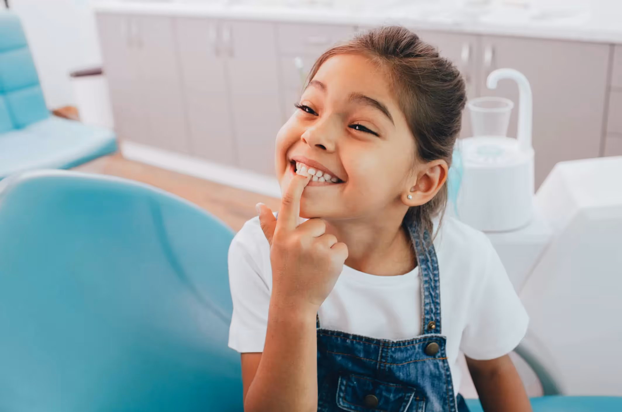 Niña feliz en el odontólogo mostrando dientes saludables