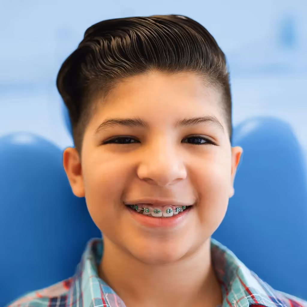 Niño utilizando aparatos de ortodoncia tradicional o brackets