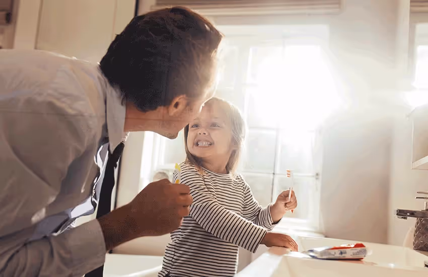 Niña cepillándose con su papá feliz