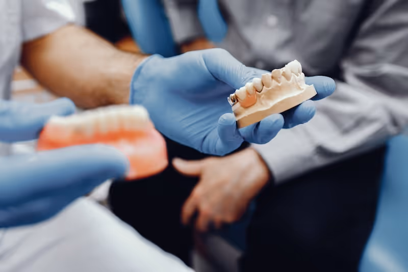 Odontólogo mostrando un modelo dental con distintos tipos de reparaciones