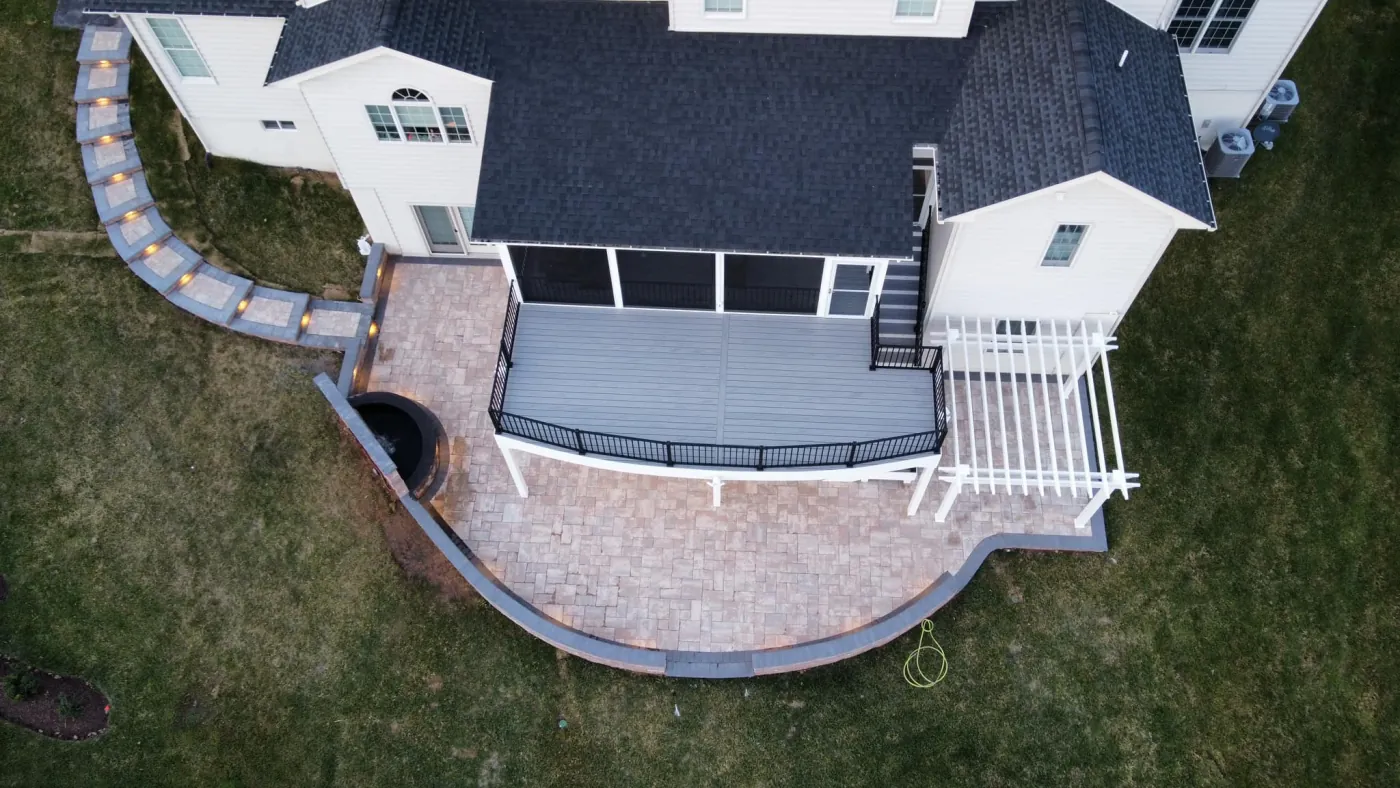 An aerial view of a rear deck with a screened porch and a paver patio with wall lighting, built by Danpri Construction