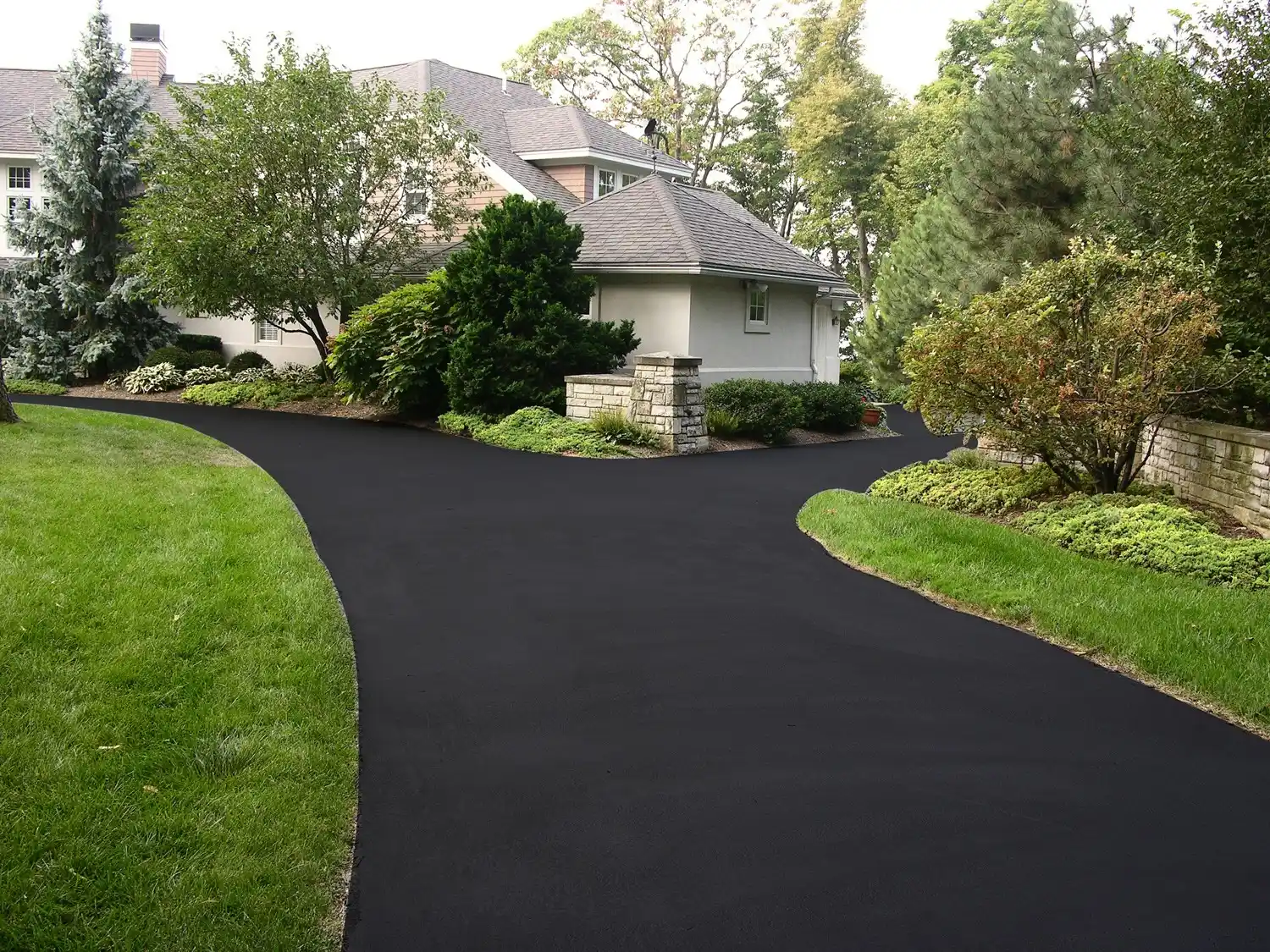 Freshly paved asphalt driveway leading to a home