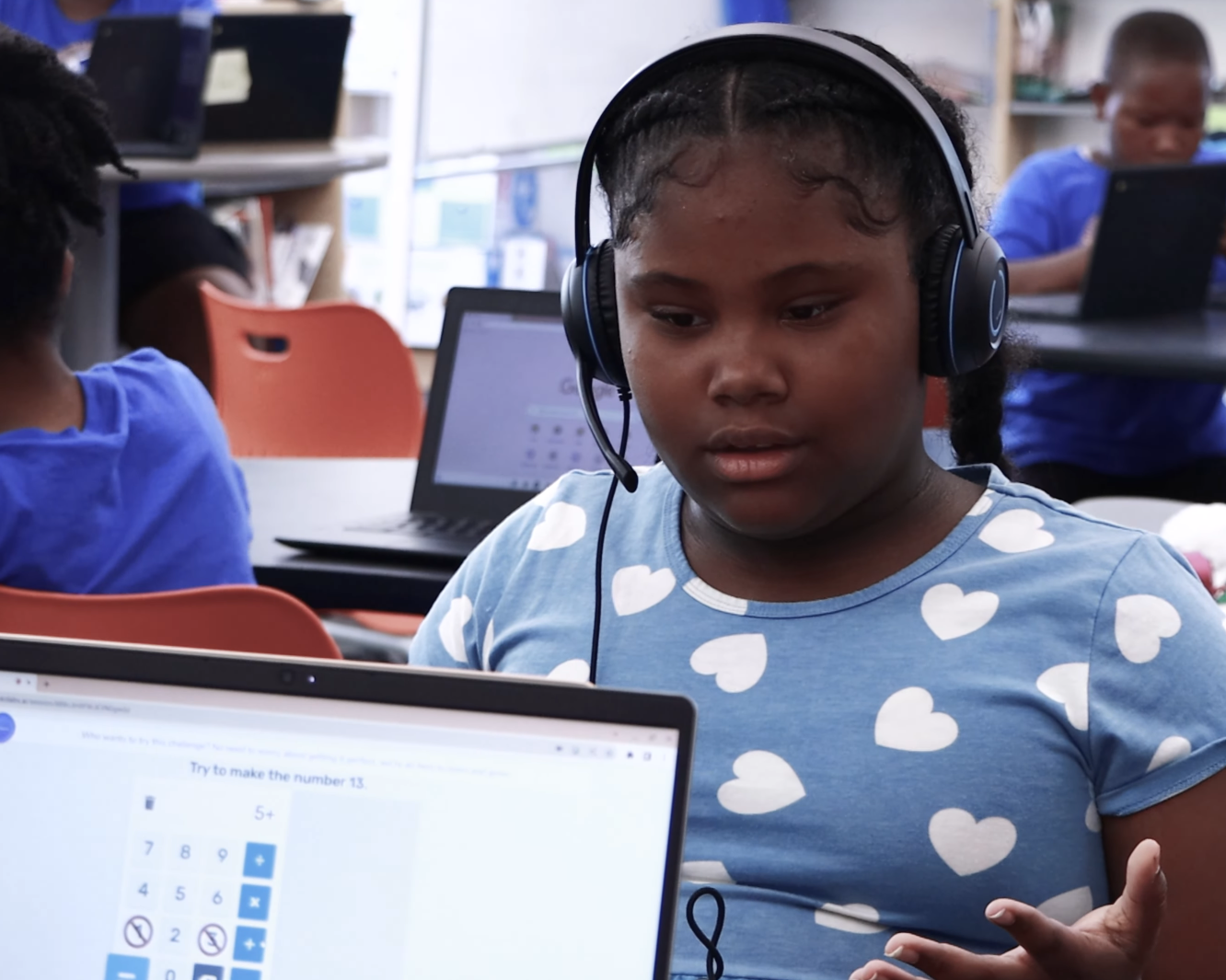 Two students wearing headsets collaborate on laptops during an OKO small-group math discourse session