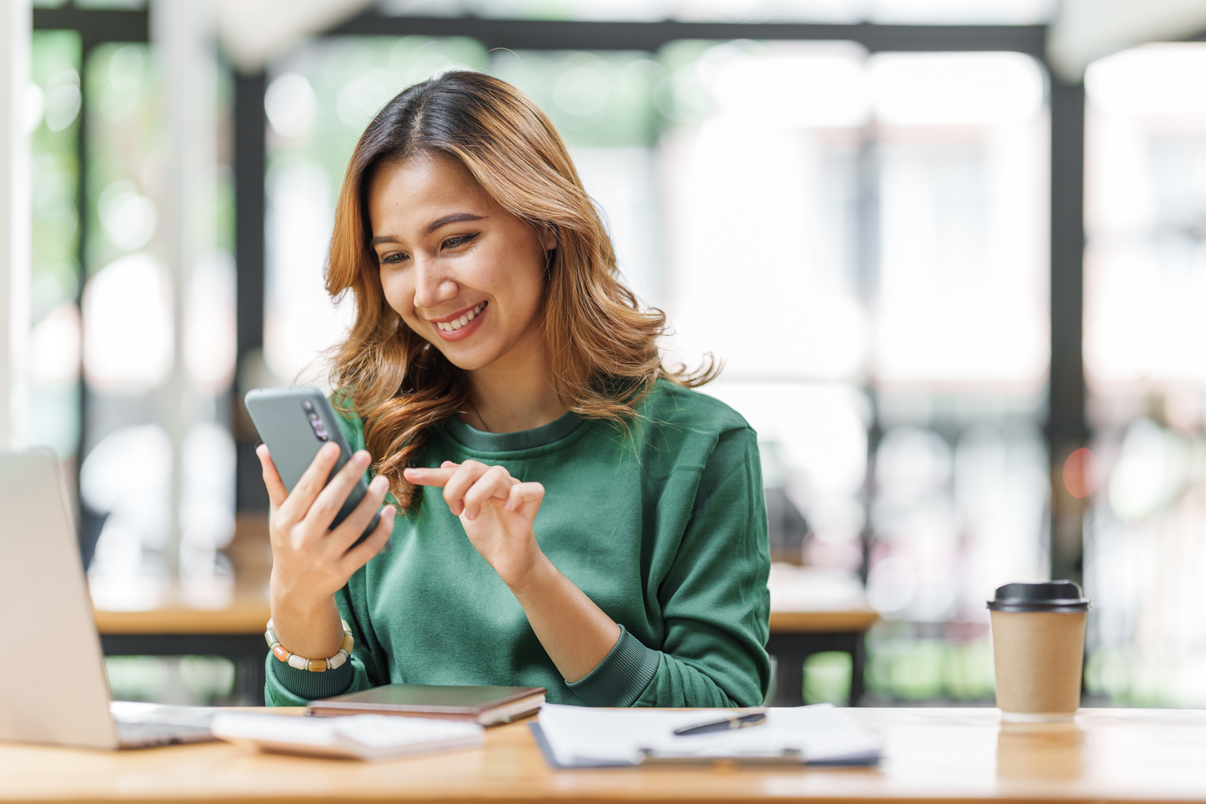 Henkilö käyttää älypuhelinta työpöydän ääressä ja opiskelee mikrokoulutusta.
