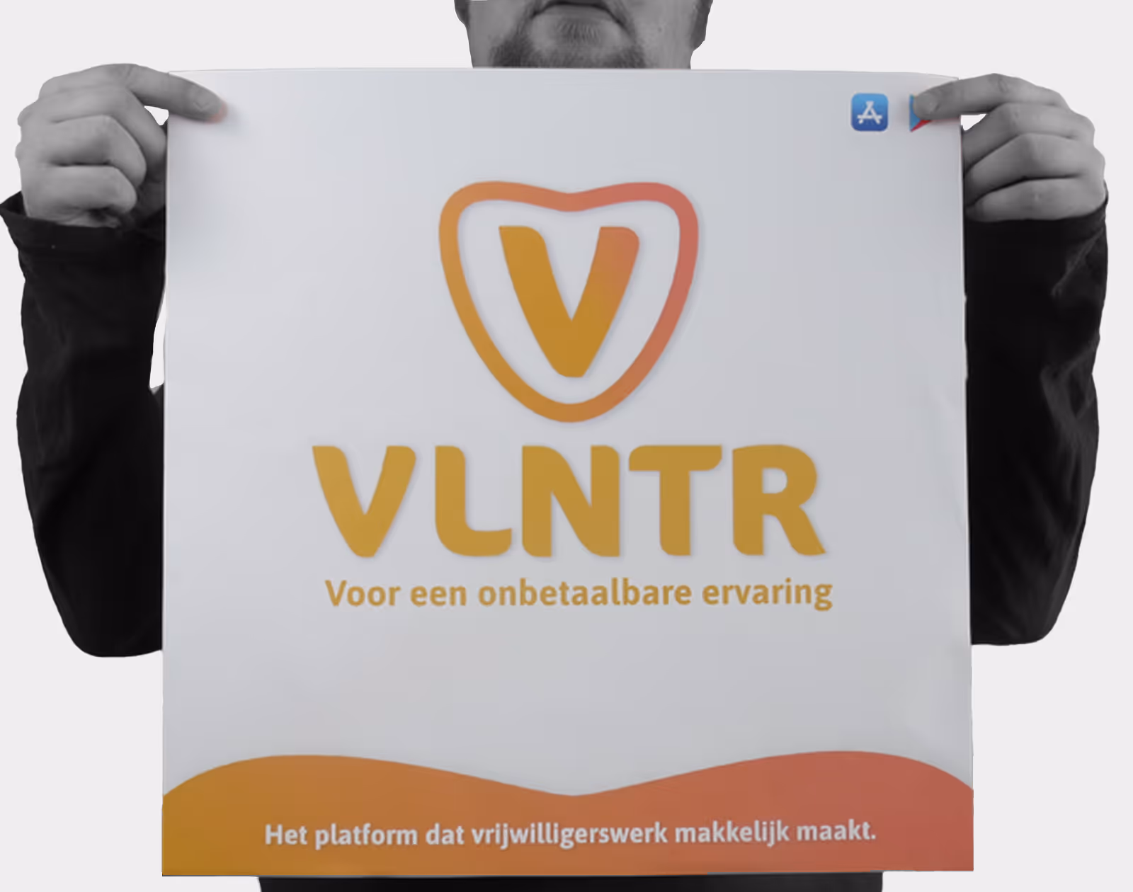 Man houdt bord vast met VLNTR-logo en tekst 'Voor een onbetaalbare ervaring', platform voor vrijwilligerswerk.