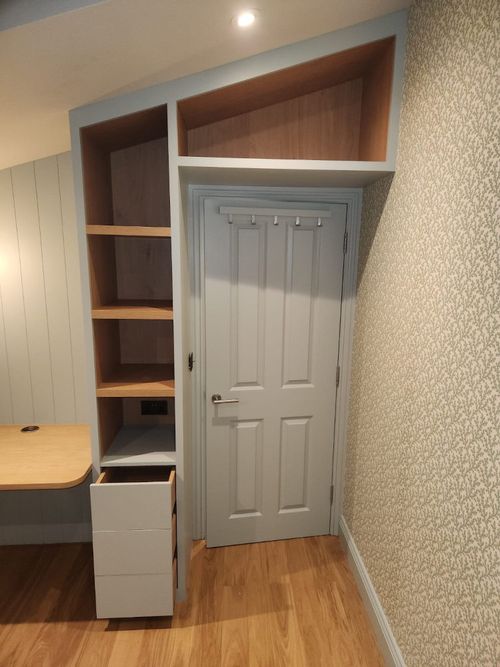 Home office, built in desk fitting with a vaulted ceiling. Shelving and draws on either side of small, wooden desktop