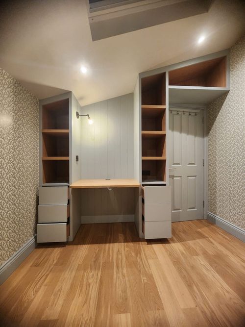Home office, built in desk fitting with a vaulted ceiling. Shelving and draws on either side of small, wooden desktop