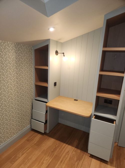 Home office, built in desk fitting with a vaulted ceiling. Shelving and draws on either side of small, wooden desktop