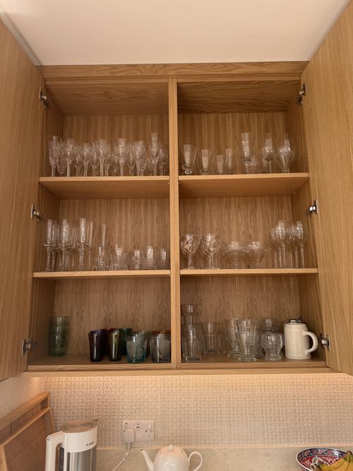Solid Oak kitchen cabinets open with glasses and mugs.