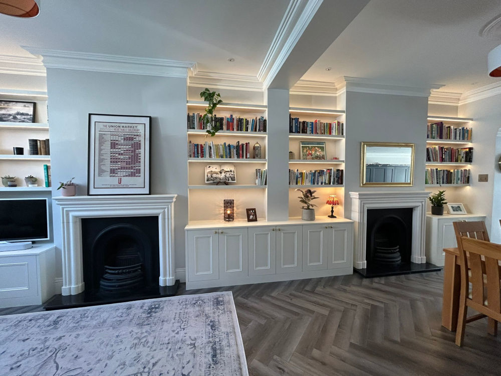 Alcove Units with shaker cabinets below and floating shelving above. Painted White with LED under light. Either side of traditional fireplace with gold framed mirror above.