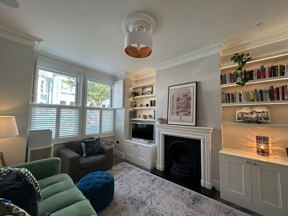Alcove Units with shaker cabinets below and floating shelving above. Painted White with LED under light. Either side of traditional fireplace with gold framed mirror above.