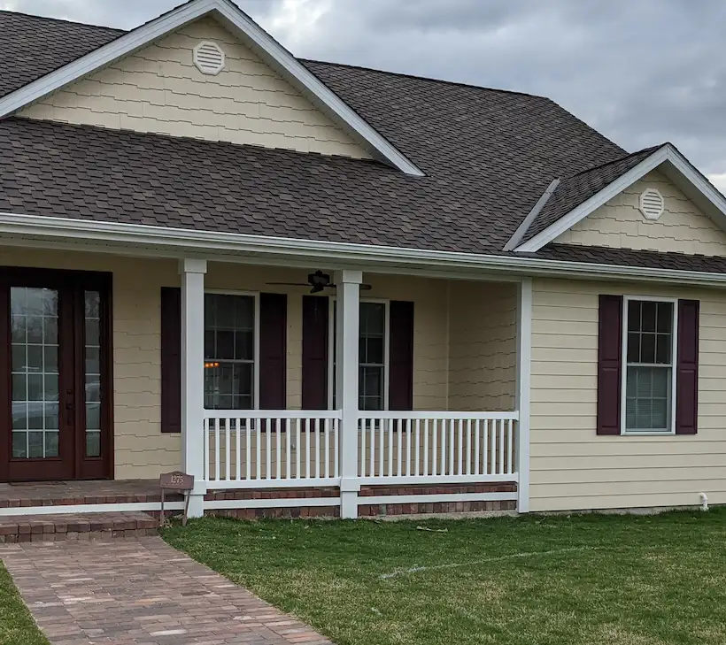 A picture of a white vinyl privacy fence with vertical planks and decorative post caps.