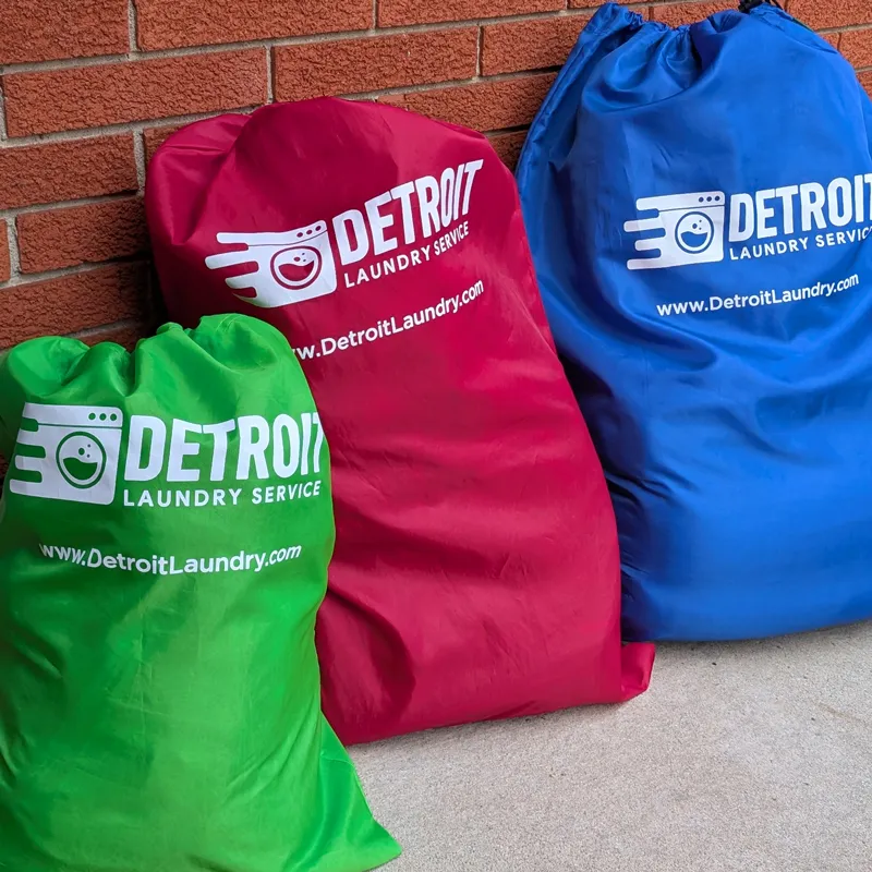 Green, red, and blue Detroit Laundry Service bags waiting at a customer's door