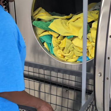 Detroit Laundry Service team member standing with a large red laundry bag inside the laundromat