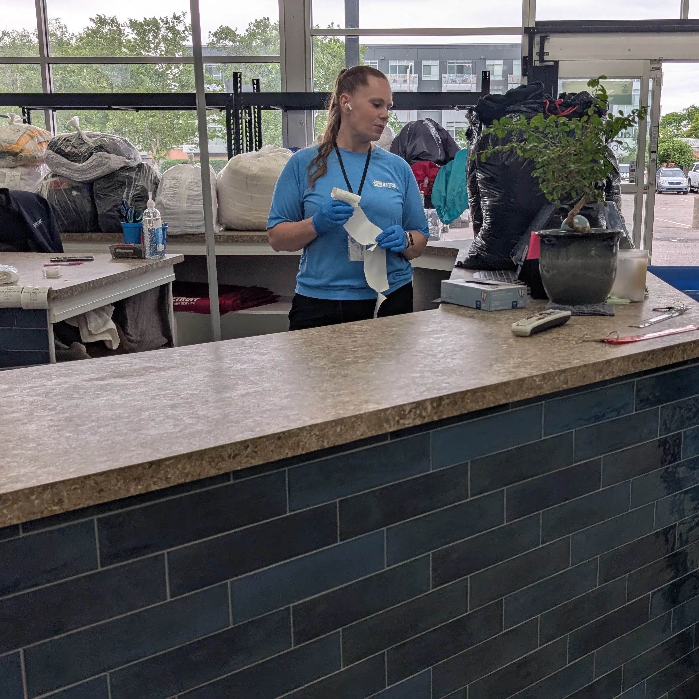 Detroit Laundry Service attendant folding laundry behind the drop-off counter