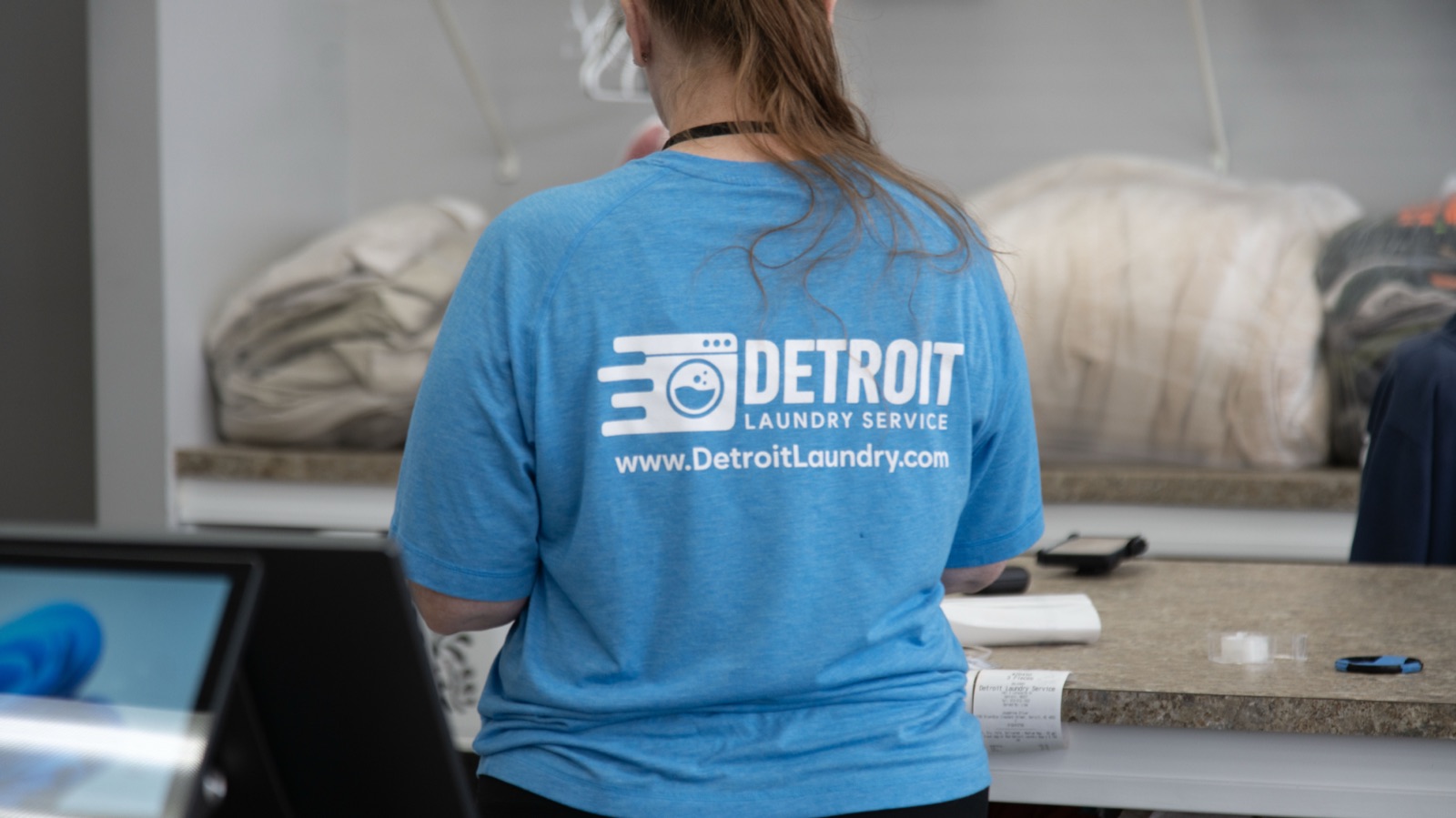 Detroit Laundry Service team member in a branded shirt processing a laundry order