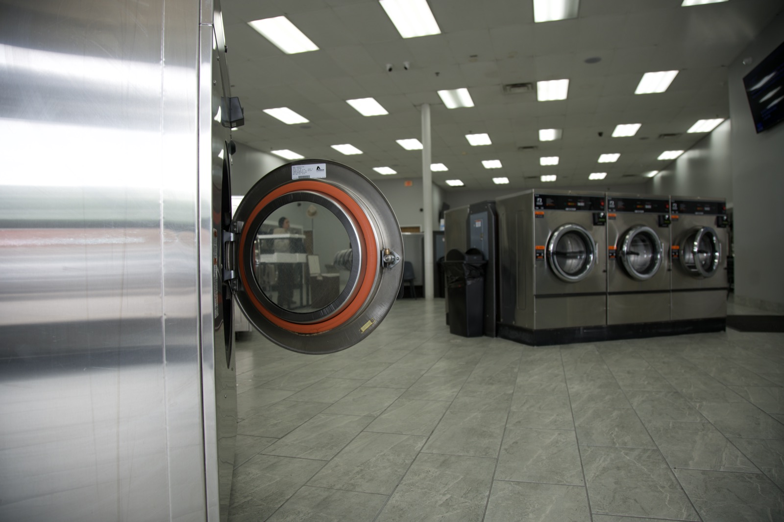 Open commercial washer door with the laundry floor behind it
