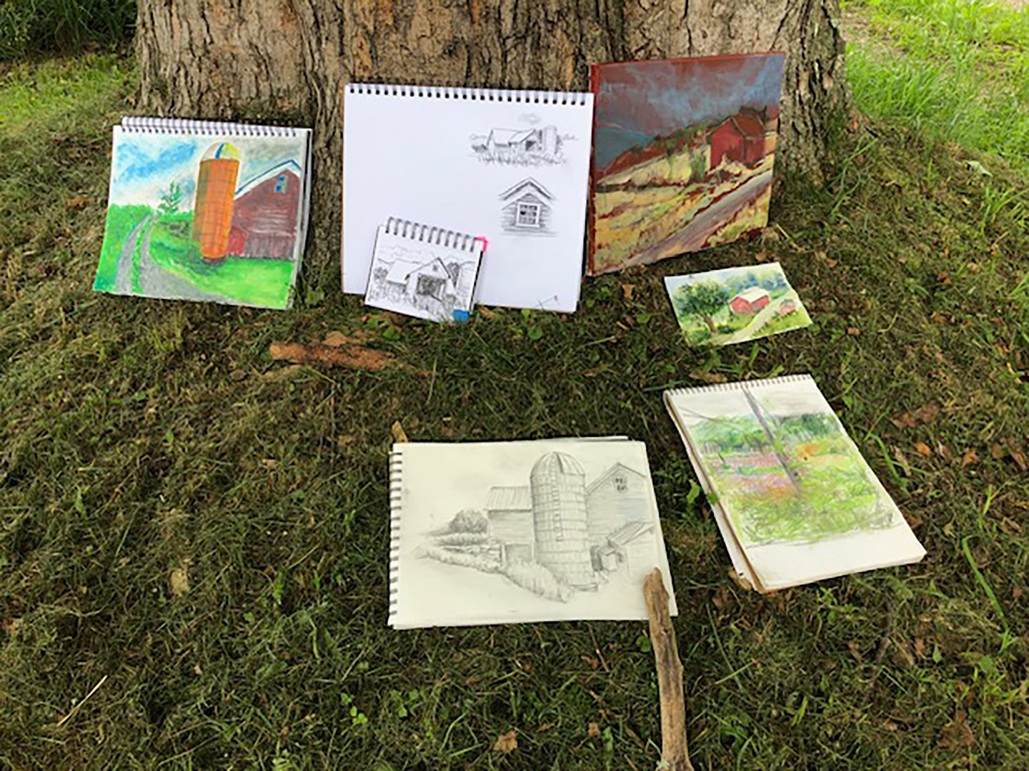 Collection of drawing and paintings of barn arranged at base of tree