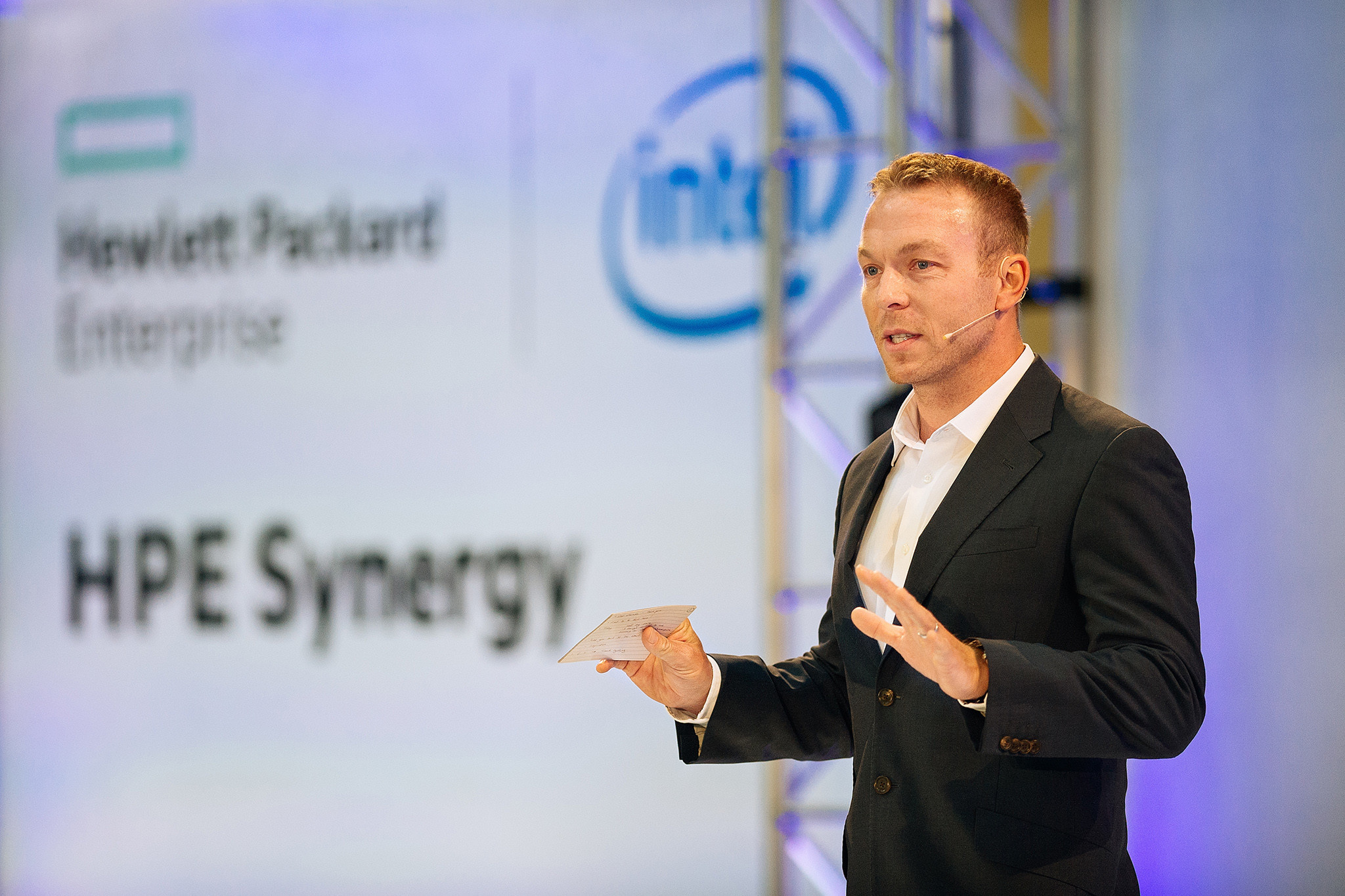 A man in a suit stands in front of a sign that says "Intel Sync Energy".