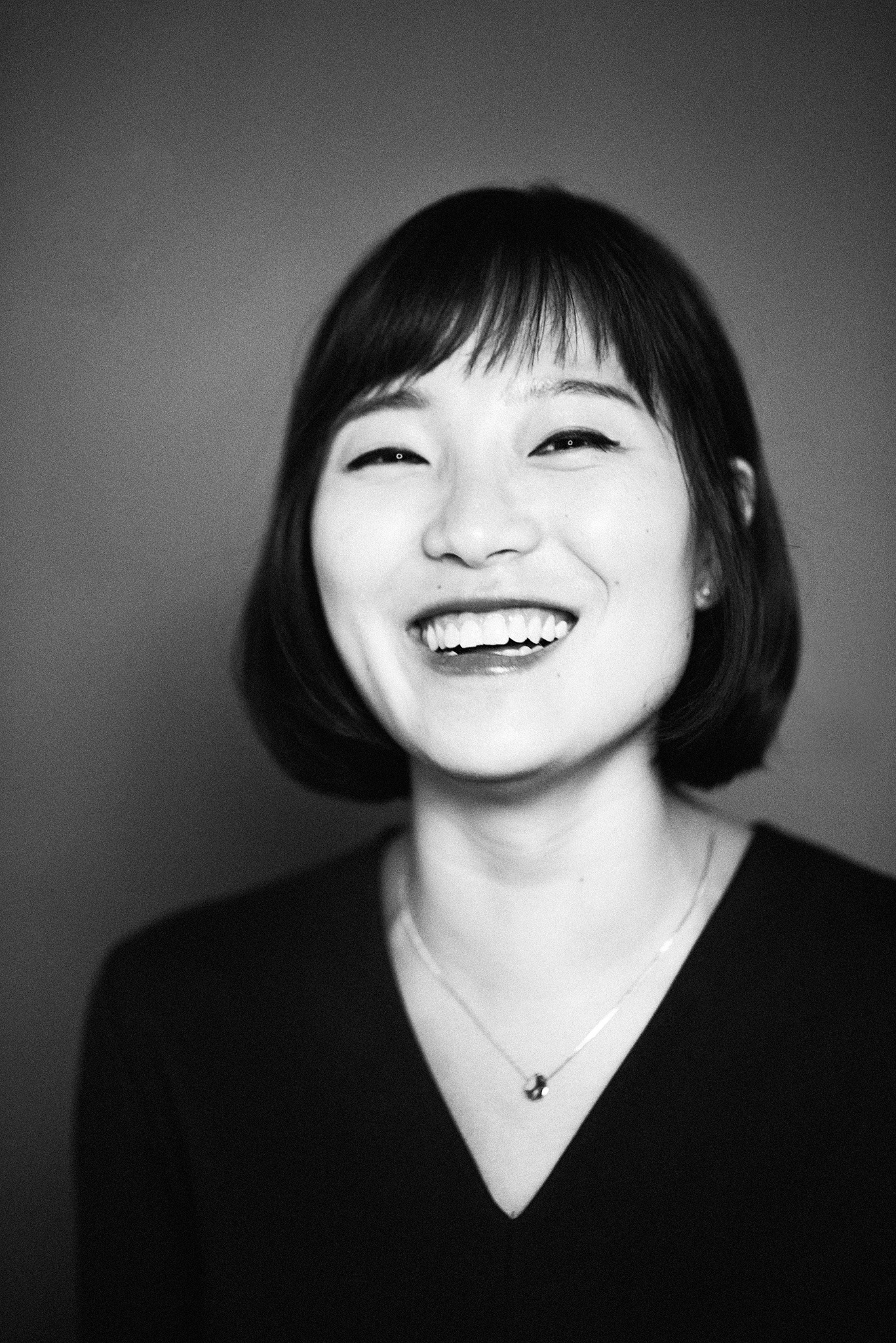 Black and white portrait of a cheerful woman with a short bob haircut, smiling brightly