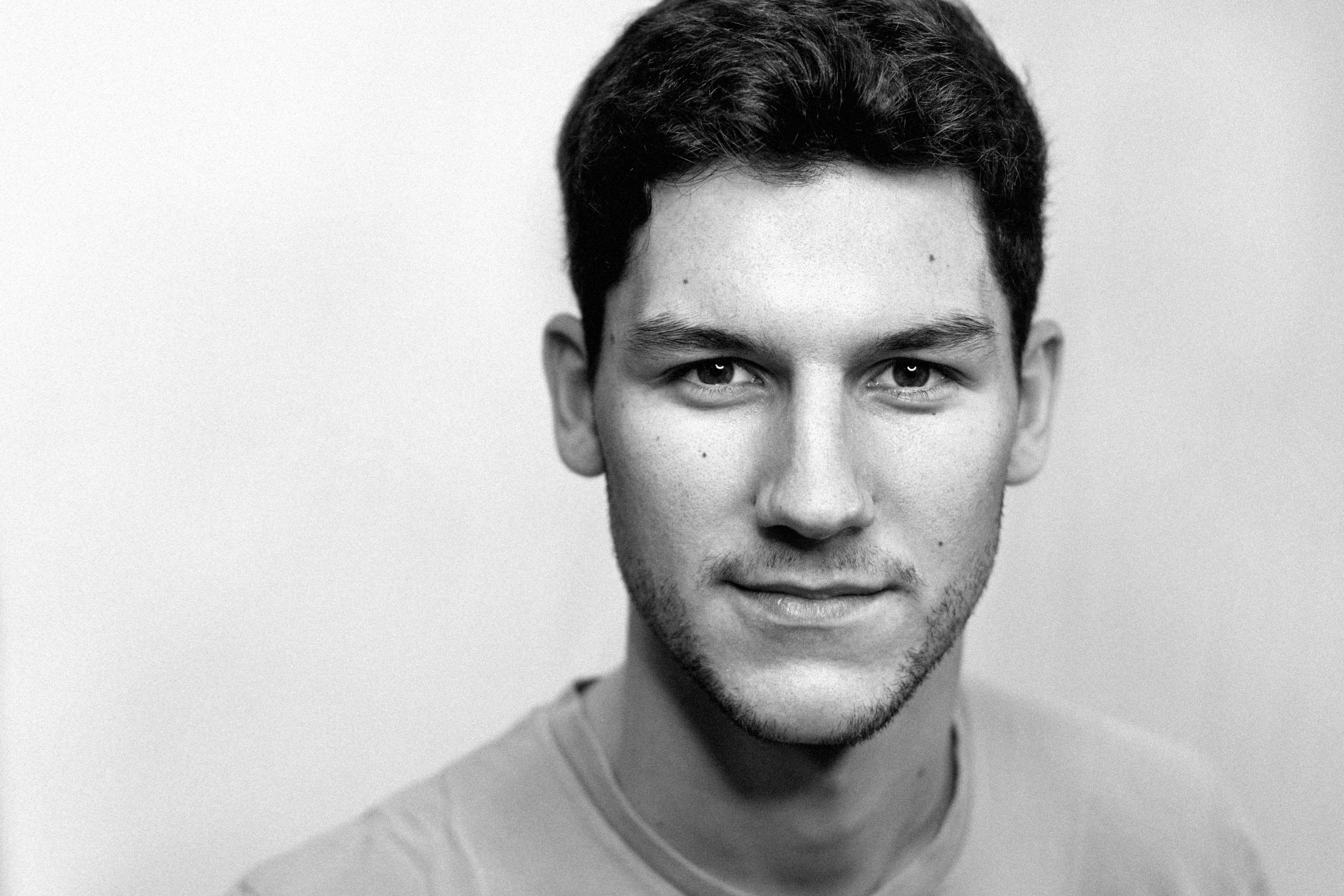 Black and white portrait of a young man with short hair, gazing directly at the camera