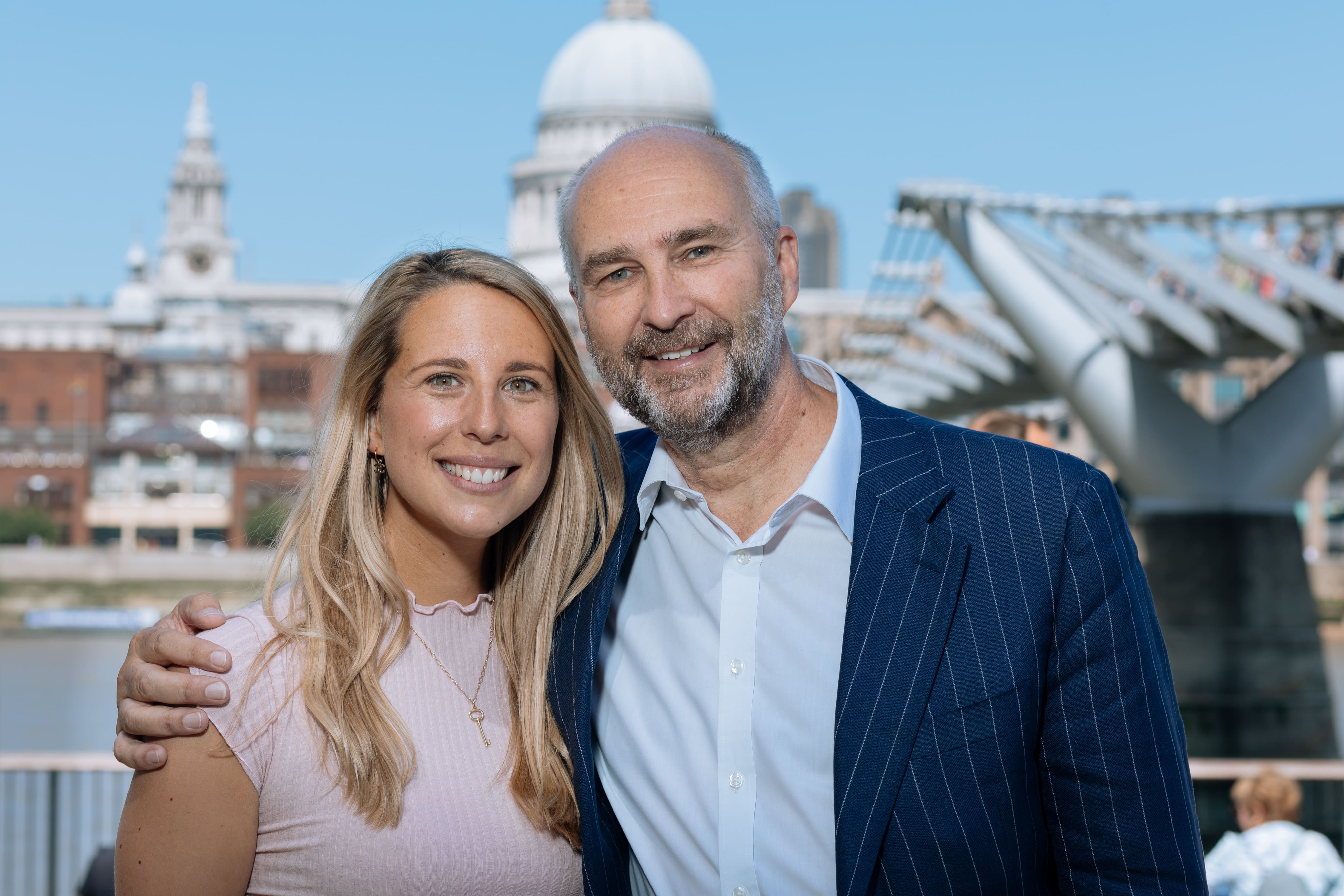 A man and woman pose for a picture in front of a city skyline.