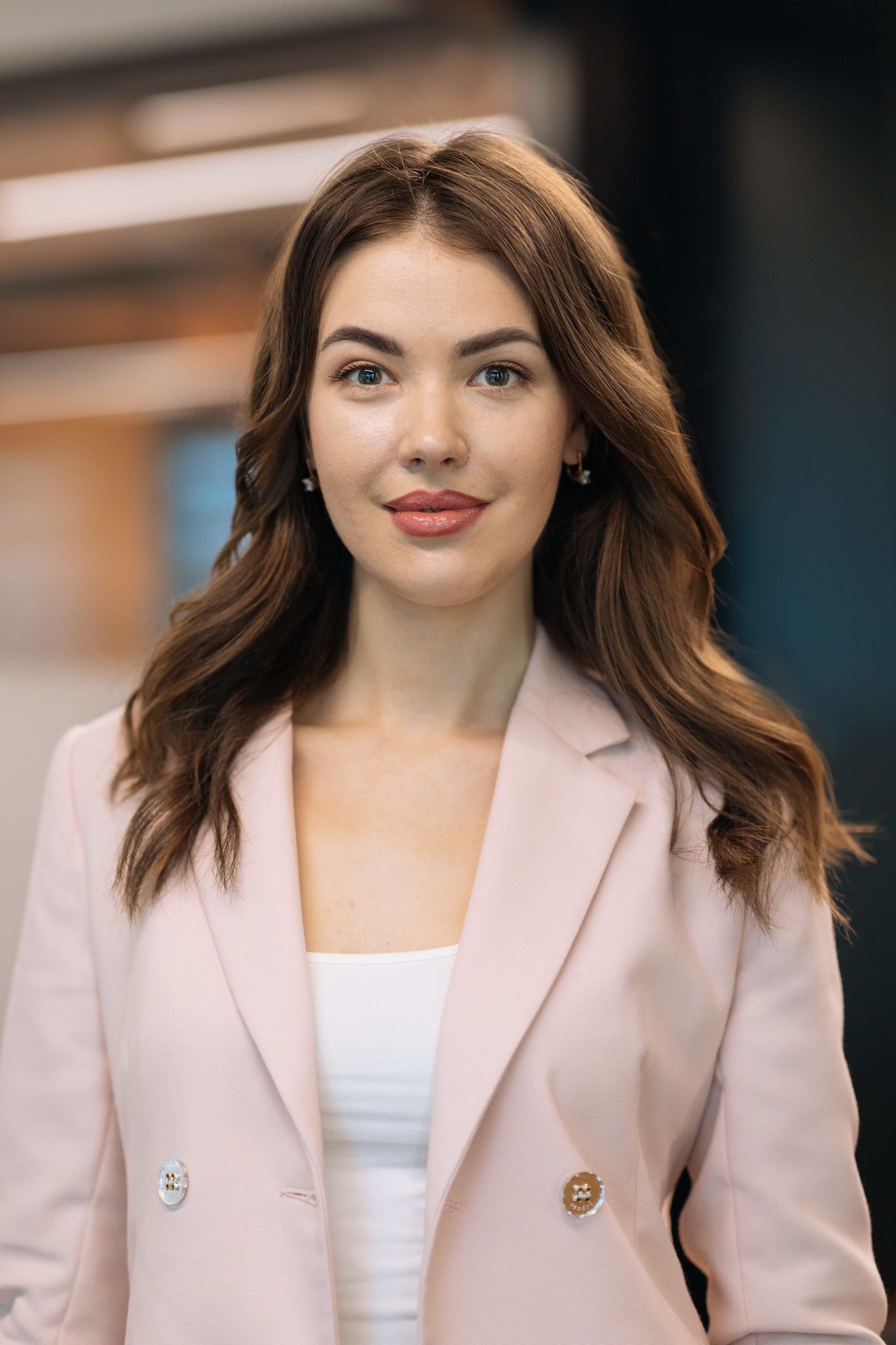 A woman wearing a pink jacket and white shirt.