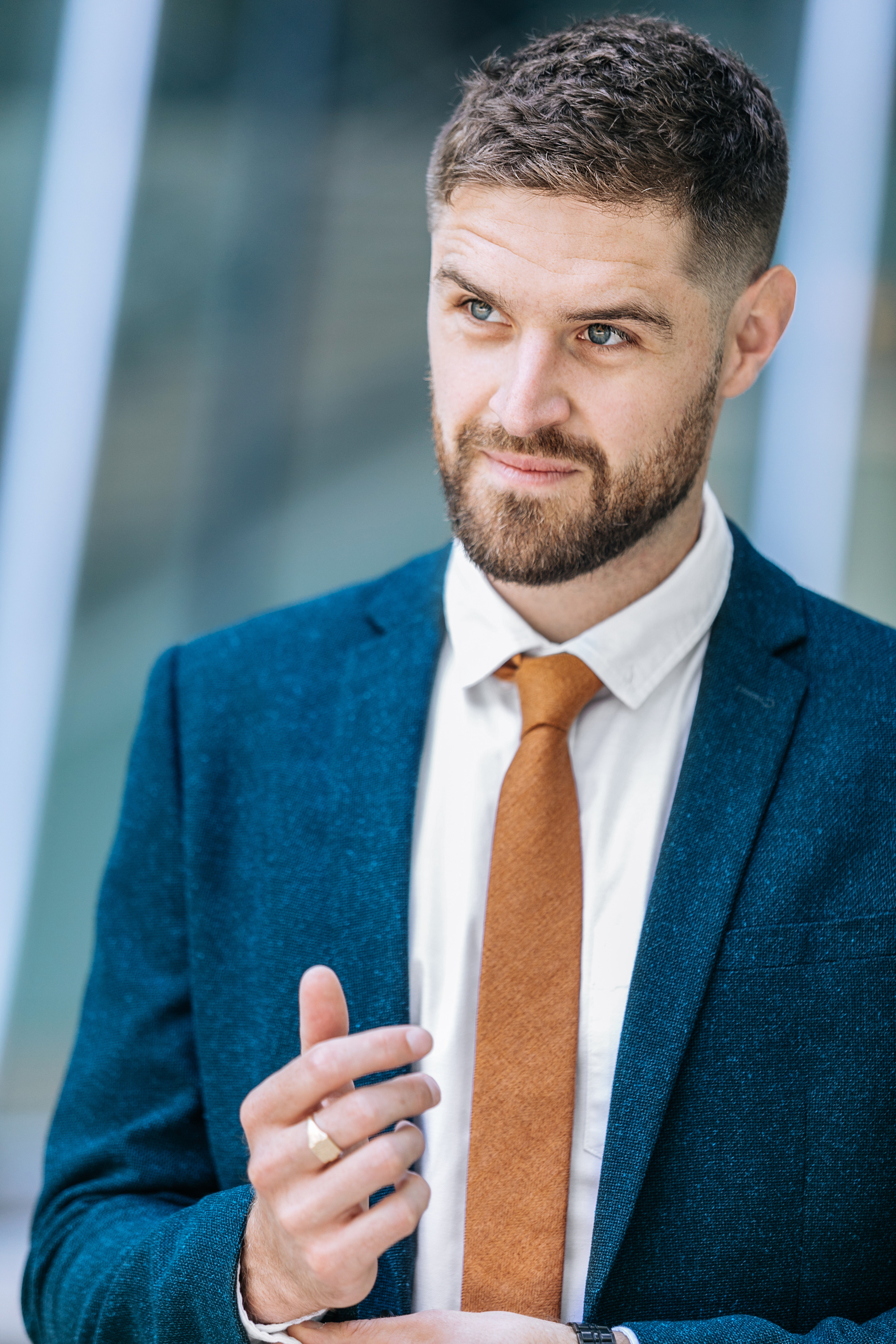 A man wearing a blue suit and an orange tie.