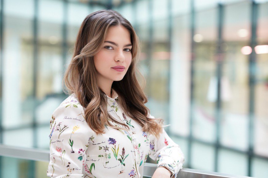 A woman in a floral shirt is posing for a picture.